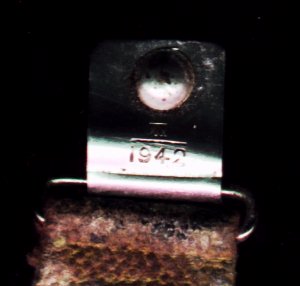 The infantry helmets chin strap clasp, with its date of manufacture.